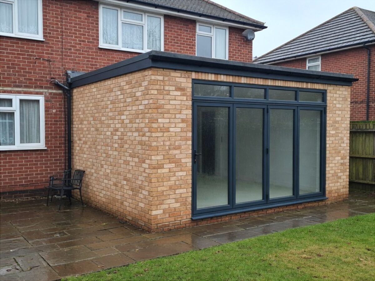 Buff brick rear extension with grey aluminium bifold doors on a red-brick semi